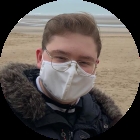 Cave, on a beach, wearing a mask