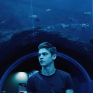 Zeus, a young man in a walk-in aquarium. The light shining through the water illuminates everything in a deep blue hue
